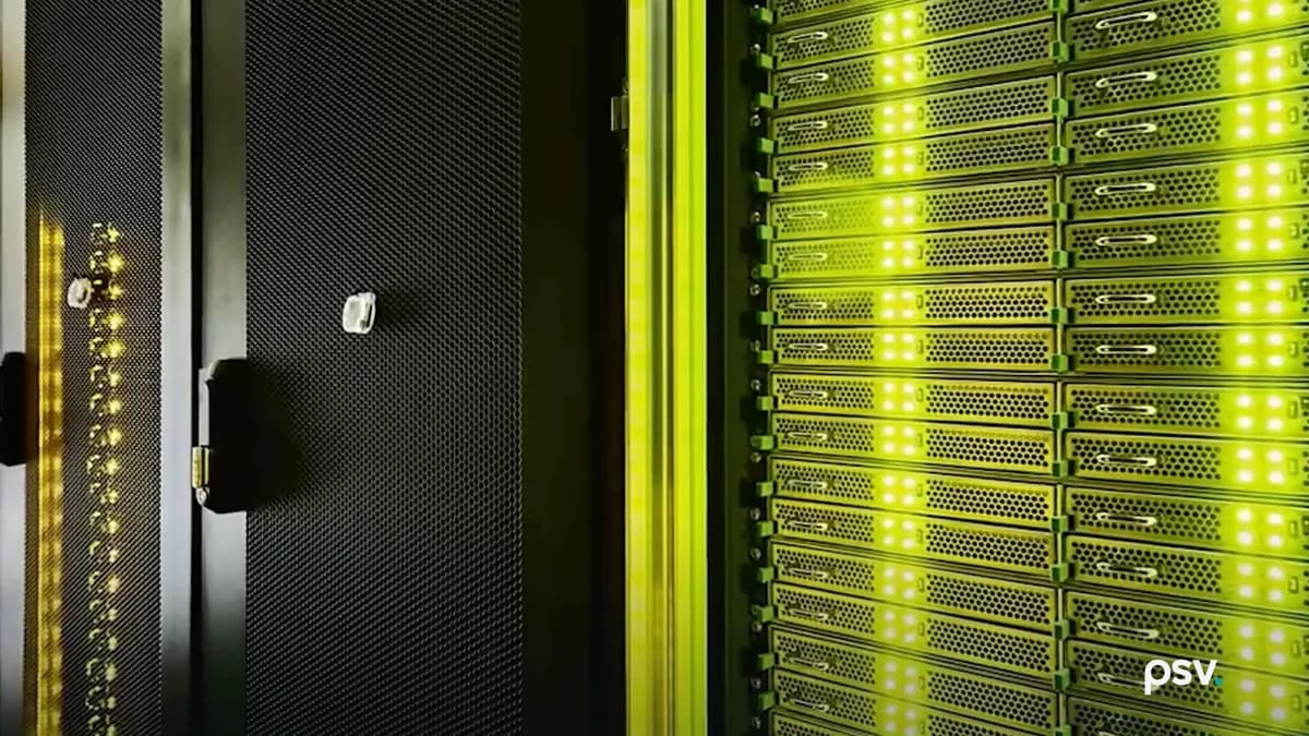 Inside a dim data hall: an open perforated black cabinet door on the left, and to the right a tall rack face packed with rows of server units, their status lights glowing white and green under green aisle lighting