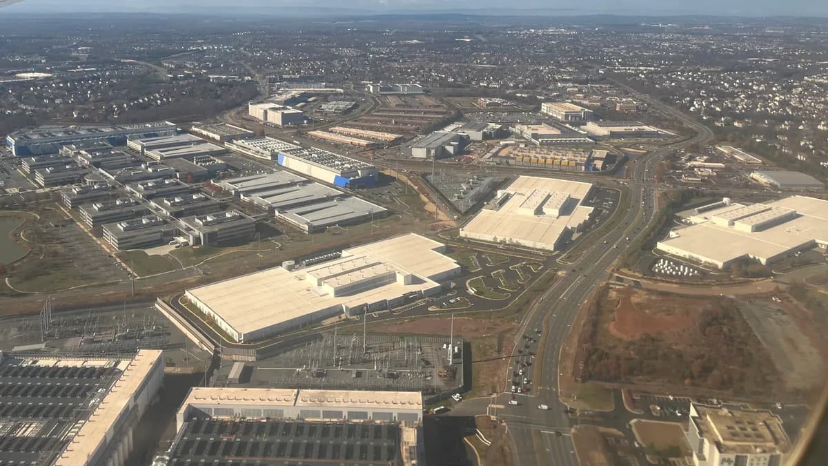 Aerial view of Loudoun County, Virginia: rows of long, flat-roofed data center buildings with rooftop cooling units, set among parking lots, service roads and other commercial buildings