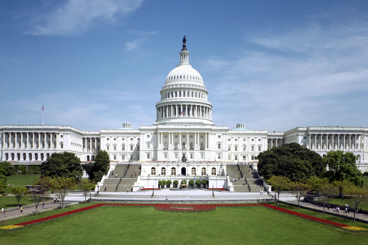 The west front of the United States Capitol in Washington, DC under a clear sky, with the dome centered above the steps and the spring tulip beds on the lawn below The west front of the United States Capitol in Washington, DC under a clear sky, with the dome centered above the steps and the spring tulip beds on the lawn below
